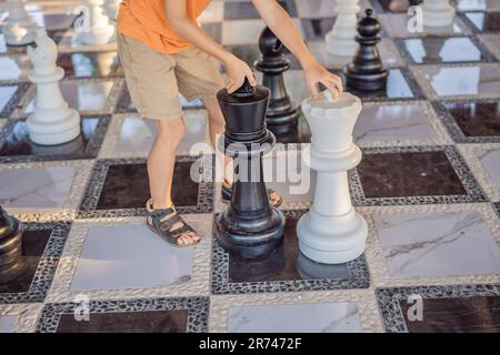 Vater und Sohn spielen Schach und verbringen Zeit zusammen im Freien. Kind spielt Schach Stockfoto