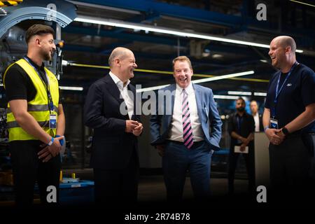 Köln, Deutschland. 12. Juni 2023. Bundeskanzler Olaf Scholz (2. von links, SPD) und William Clay Ford (3. von links), CEO von Ford, sprechen mit Mitarbeitern bei der Zeremonie vor der Eröffnung des Ford Cologne Electric Vehicle Center. Das Kölner Werk wird Fords erstes EV-Zentrum in Europa sein. Kredit: Marius Becker/dpa/Alamy Live News Stockfoto