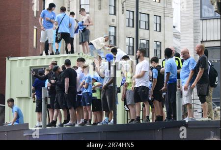 Manchester, Großbritannien. 12. Juni 2023. Die man City-Fans standen auf einer Baustelle und versuchten, die Siegesparade mit offenem Oberdeck im Zentrum von Manchester, Großbritannien, zu sehen, um die Erfolge ihres Clubs zu würdigen, der die Höhen gewonnen hat: Die Premier League, der FA Cup und die Champions League. Am Samstag besiegte man City Inter Mailand in Istanbul und sicherte sich den Champions League-Sieg. Die Parade der offenen Busse fuhr durch das Stadtzentrum von Manchester und beobachtete von großen, begeisterten Massen, trotz Gewitter und starkem Regen. Kredit: Terry Waller/Alamy Live News Stockfoto