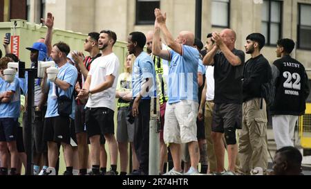 Manchester, Großbritannien. 12. Juni 2023. Die man City-Fans standen auf einer Baustelle, um die Siegesparade mit offenem Oberdeck im Zentrum von Manchester, Großbritannien, zu sehen, um die Erfolge ihres Clubs zu feiern, der die Trebel gewann: Die Premier League, der FA Cup und die Champions League. Am Samstag besiegte man City Inter Mailand in Istanbul und sicherte sich den Champions League-Sieg. Die Parade der offenen Busse fuhr durch das Stadtzentrum von Manchester und beobachtete von großen, begeisterten Massen, trotz Gewitter und starkem Regen. Kredit: Terry Waller/Alamy Live News Stockfoto