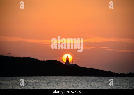 In der Dämmerung ist die Sonne hinter dem Leuchtturm. Das Fugui Cape Lighthouse in Shimen. Taiwan Stockfoto