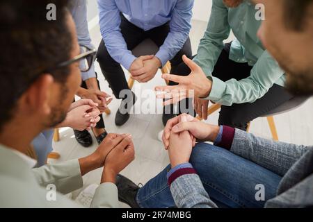 Nahaufnahme von Personen, die im Kreis sitzen und miteinander kommunizieren Stockfoto