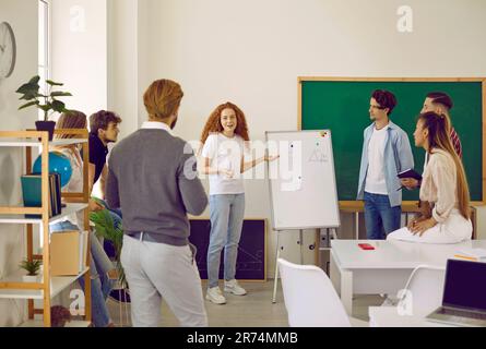 Gruppe von Schülern zusammen mit Lehrern, die jungen Mädchen bei der Präsentation zuhören Stockfoto