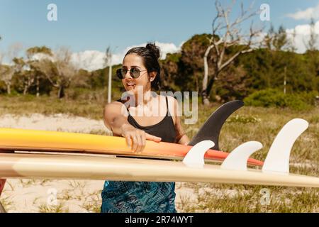 Eine wunderschöne junge Frau an einem Sandstrand, die sich bereit macht, im Meer zu surfen Stockfoto