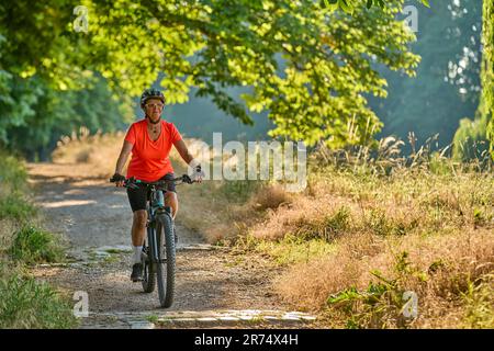 Attraktive Seniorin, die mit ihrem elektrischen Mountainbike im Stadtpark Stuttgart, Baden-Württemberg, fährt Stockfoto