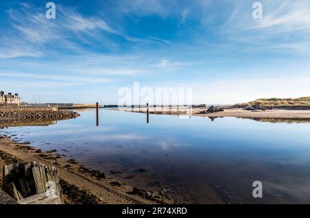 Es gibt Pfosten mit Reflexion im Wasser, bereit für den Bau einer neuen Brücke zum Strand von der Vorderseite in Lossiemout Stockfoto