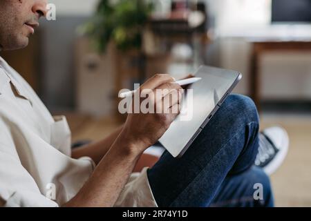 Nahaufnahme eines Mannes, der auf einem digitalen Tablet zeichnet. Stockfoto