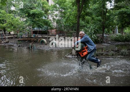 KHERSON, UKRAINE - 12. Juni 2023: Rettungshelfer schultert einen Mann aus einem überfluteten Gebiet Stockfoto