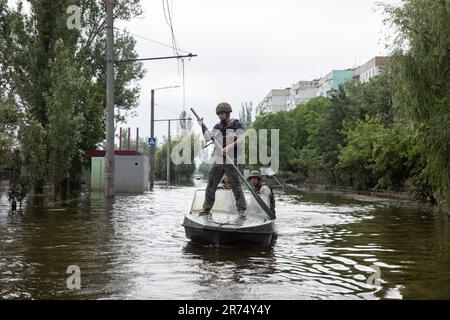 KHERSON, UKRAINE - 12. Juni 2023: Freiwillige und Rettungskräfte fahren mit dem Boot durch die überfluteten Straßen von Kherson Stockfoto