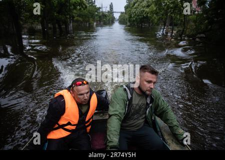 KHERSON, UKRAINE - 12. Juni 2023: Freiwillige und Rettungskräfte fahren mit dem Boot durch die überfluteten Straßen von Kherson Stockfoto