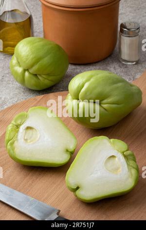 Ganze und halbierte frische Chayote auf einem Schneidebrett, Nahaufnahme Stockfoto