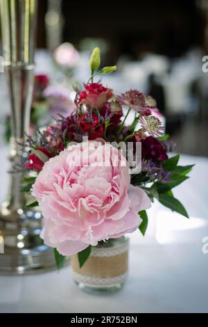 Blumenstrauß mit Pfingstrosen in einer kleinen Vintage-Vase auf einem festlichen Tisch Stockfoto