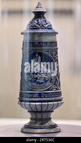 PRODUKTION - 12. Juni 2023, Thüringen, Eisenach: In der Wartburg-Ausstellung „Mythos Wartburg“ ist ein Becher mit Deckel und einem Bild der Wartburg zu sehen. Die Sonderausstellung "Wartburg-Mythos". 10 Questions to the Ideal Castle“ wird am 13. Juni eröffnet und bis zum 07. Januar 2024 ausgestellt. 1999 wurde die Wartburg als erstes und einziges Schloss Deutschlands von der UNESCO zum Weltkulturerbe erklärt. Mit der Ausstellung soll erforscht werden, warum die Wartburg so stark im öffentlichen Bewusstsein verankert ist und wie dieses reiche historische und kulturelle Erbe fortbestehen kann Stockfoto