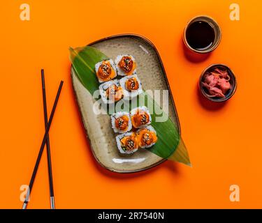 Ein Blick von oben auf frische Sushi-Brötchen auf orangefarbenem Hintergrund Stockfoto