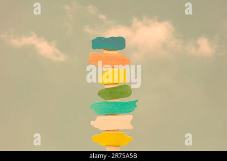 Bunte hölzerne Richtungspfeilschilder auf einem Holzmast Stockfoto