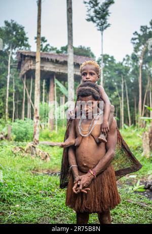 Frau des Korovai-Stammes mit einem Kind. Stamm der Korowai (Kombai, Kolufo). 10. Juni 2016 in Onni Village, Neuguinea, Indonesien Stockfoto