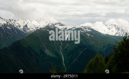 Panoramablick auf die schneebedeckten Gipfel. Bergkette des Großkaukasus in Georgien, Svaneti-Region. Hügel mit üppigen Weiden, scharfe Gipfel Stockfoto