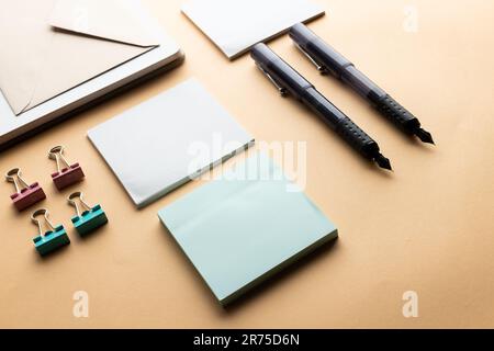 Flache Anordnung von schwarzen Stiften, Umschlägen, Büroklammern und Notizen mit Kopierbereich auf gelbem Hintergrund. Schulmaterial, Schreiben, Malen, Zeichnen, lear Stockfoto
