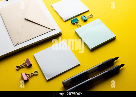 Flache Lage aus schwarzen Stiften, Umschlag und weißem Papier mit Kopierbereich auf gelbem Hintergrund. Schulmaterial, Schreiben, Malen, Zeichnen, Lernen, Schule Stockfoto