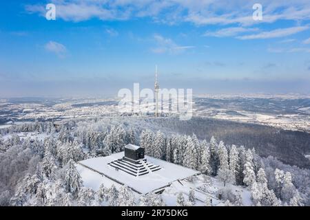 Ein Luftblick auf üppige schneebedeckte Wälder mit Avala Tower im Hintergrund. Beli Potok, Serbien. Stockfoto