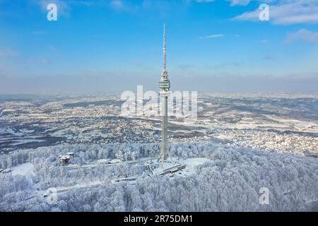 Ein Luftblick auf üppige schneebedeckte Wälder mit Avala Tower im Hintergrund. Beli Potok, Serbien. Stockfoto