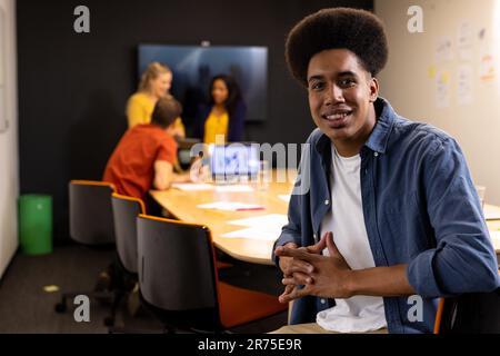 Porträt eines fröhlichen, birassischen, zwanglosen Geschäftsmanns mit lächelndem Afro im Tagungsraum Stockfoto