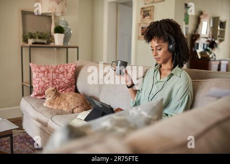 Frau, die ein Tablet benutzt, während sie zu Hause mit ihrer Katze sitzt Stockfoto