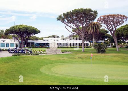Begrüßungsschild am Golfklub und Golfplatz Vale do Lobo mit Golfbuggys und Golfschlägern und Blick auf das Clubhaus und Restaurant über dem 18. Stockfoto