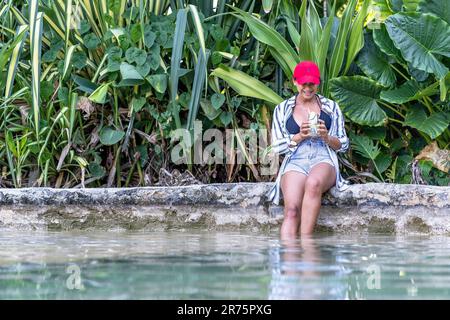 Nordamerika, Karibik, Großantillen, Hispaniola, Dominikanische Republik, Sama Province, Sama Peninsula, El Limón, Sama Eco Lodge, Pretty Latina liegt am Pool mit einem Cocktail Stockfoto