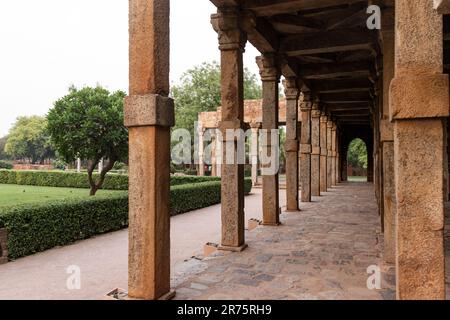 Ein Pfad, der mit Säulen gesäumt ist. Quwwat-ul-Islam-Moschee im Qutb Minar Komplex. Delhi, Indien. Stockfoto