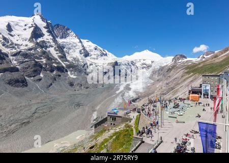 Menschen auf der Kaiser-Franz-Josefs-Höhe mit Großglockner, Johannisberg, Pasterzen-Gletscher und Bahnhof im Hintergrund unter einem hellblauen Himmel Stockfoto