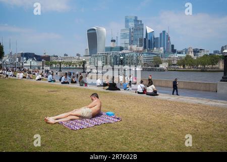 London UK. 13 . Juni 2023 . Ein Mann sonnt sich oben in Pottrs Field am Londoner Flussufer, während ein weiterer heißer Tag mit hohen Temperaturen um 29celsius Uhr vorhergesagt wird, da einige Teile Großbritanniens eine Hitzewelle erleben, mit Wetterwarnungen für Gewitter und Regen. Kredit: amer Ghazzal/Alamy Live News Stockfoto