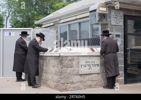 3 jüdische Männer beten am Grabstein des Ribnitz Rebbe, da man annimmt, dass Gebete in der Nähe der Gerechten erhellt werden. In Mnsey New York. Stockfoto