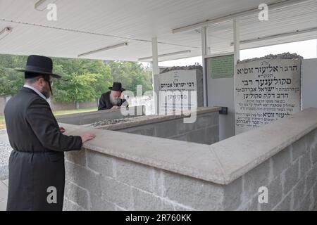 Orthodoxe jüdische Männer beten am Grabstein des 1. Skuliners Rebbe und seines Sohnes in einem Oel auf dem Vizhnitz-Friedhof in Monsey, New York, 2023. Stockfoto