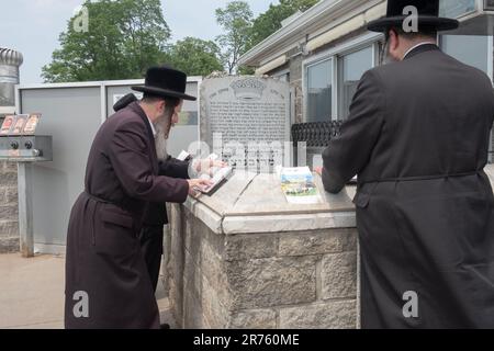 Orthodoxe jüdische Männer beten am Grabstein des Ribnitz Rebbe, da man annimmt, dass Gebete in der Nähe der Gerechten verstärkt werden. In MOnsey New York. Stockfoto