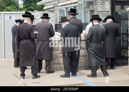 Orthodoxe jüdische Männer beten am Grabstein des Ribnitz Rebbe, da man annimmt, dass Gebete in der Nähe der Gerechten verstärkt werden. In Mnsey New York. Stockfoto