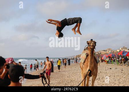 Gaza, Palästina. 13. Juni 2023. Kinder reiten auf einem Kamel am Strand von Deir El Balah. Palästinensische Familien strömen zum Gazastreifen, um aufgrund der hohen Temperaturen am 11. Juni 2023 im zentralen Gazastreifen Deir al-Balah, Palästinensische Gebiete, eine Pause einzulegen. Foto: Ramez Habboub/ABACAPRESS.COM Kredit: Abaca Press/Alamy Live News Stockfoto