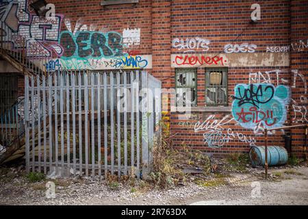 Eine Wand, die mit Graffiti bedeckt und vandalisiert wurde. Konzept von Verfall, Vernachlässigung oder Verlassen. Stockfoto