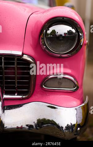 Izmir, Türkei - 3. Juni 2023: Fokussierte Nahaufnahme eines einzelnen Scheinwerfers auf einem rosa 1955 Chevrolet Belair bei einem Oldtimer-Event Stockfoto