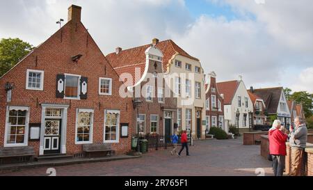 Idyllische alte Häuser in Greetsiel, einer kleinen malerischen Fischerstadt in Nordfriesien. Einige Touristen laufen kurz vor Beginn der Sommersaison herum. Stockfoto