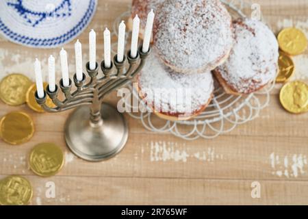 Frohes Chanukka. Chanukka altes Menorah vor dem Hintergrund der israelischen Flagge mit Sonnenlicht oder Bokeh auf weißem Holzhintergrund. Religionsbild der juden Stockfoto