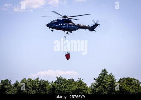 13. Juni 2023, Mecklenburg-Vorpommern, Lübtheen: Ein Helikopter der Bundespolizei wirft Feuerlöschwasser ab, um einen Waldbrand in einem ehemaligen munitionsverseuchten Ausbildungsgebiet zu bekämpfen. Am 12. Juni 2023 brachen Brände in zwei ehemaligen Ausbildungsgebieten im Südwesten Mecklenburgs aus. Foto: Jens Büttner/dpa Stockfoto