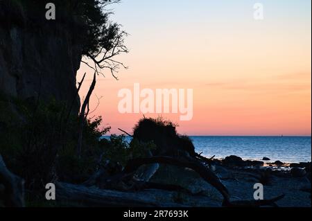 Steile Küste auf der Insel Poel bei Sonnenuntergang mit Blick auf den pastellfarbenen Himmel über Felsen in der Ostsee. Landschaftsaufnahmen von der Küste Stockfoto