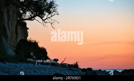 Steile Küste auf der Insel Poel bei Sonnenuntergang mit Blick auf den pastellfarbenen Himmel über Felsen in der Ostsee. Landschaftsaufnahmen von der Küste Stockfoto