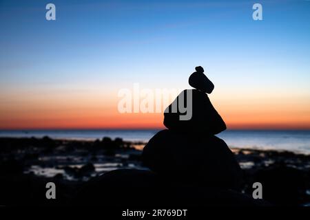Steinpyramide an der Ostsee mit Blick auf das Meer bei Sonnenuntergang und Blue Hour. Steine als Silhouette. Spirituelle Sichtweise. Landschaftsaufnahmen von Poel Island Stockfoto