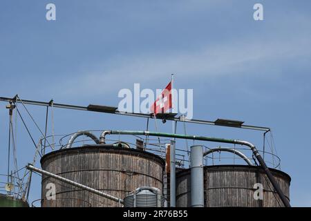 Verkürzte Holzsilos mit Schweizer Flagge am blauen Himmel. Speicherplatz kopieren. Stockfoto