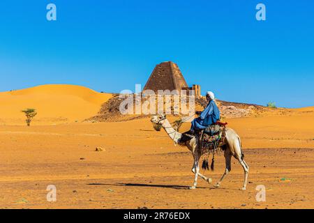 Traditionell gekleidete araber mit ihren Kamelen warten auf Touristen an den nubischen Pyramiden in meroe im sudan Stockfoto