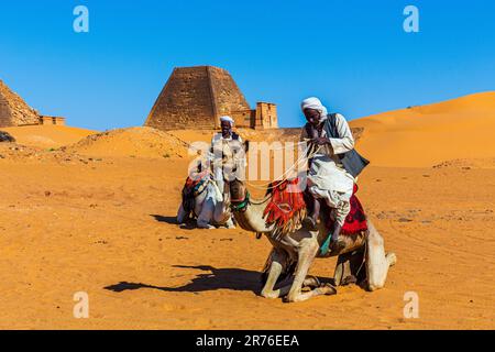 Traditionell gekleidete araber mit ihren Kamelen warten auf Touristen an den nubischen Pyramiden in meroe im sudan Stockfoto