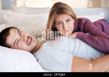 Entspannend und verliebt. Attraktives junges Paar, das zu Hause zusammen liegt. Stockfoto