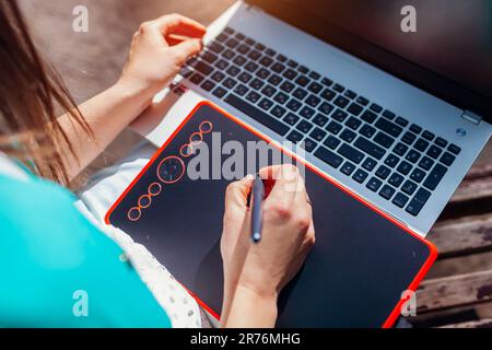 Frau, die im Freien mit Notebook und Tablet arbeitet. Grafikdesigner, die online arbeiten. Der Lehrer verwendet moderne Technologien und Geräte. Draufsicht Stockfoto
